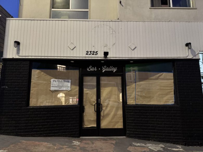 A storefront at 2325 with paper covering the windows and a sign that reads “Bar Galley.” A notice is posted on the left window. The exterior has black bricks and white paneling.