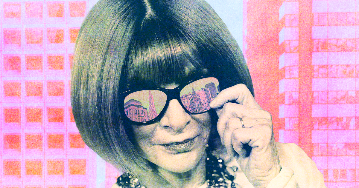 A woman with a bob haircut adjusts her large black sunglasses, reflecting city buildings, while wearing a chunky necklace against a pink cityscape background.