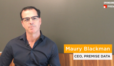 A man wearing glasses and a dark shirt is seated against a gray wall; text identifies him as Maury Blackman, CEO of Premise Data.