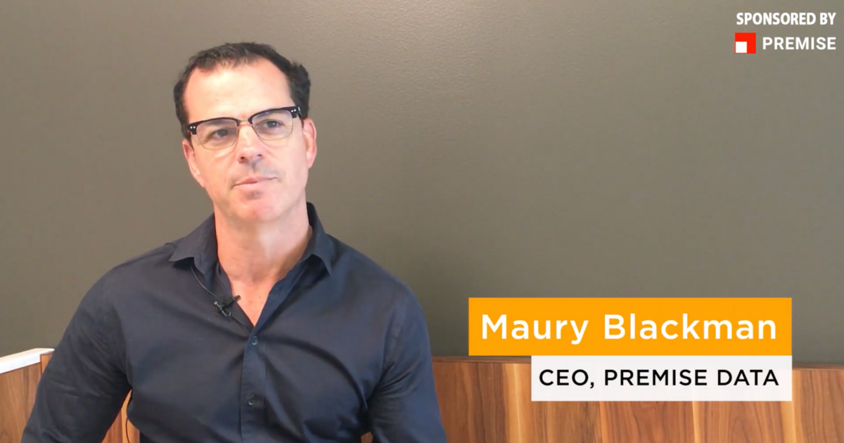 A man wearing glasses and a dark shirt is seated against a gray wall; text identifies him as Maury Blackman, CEO of Premise Data.