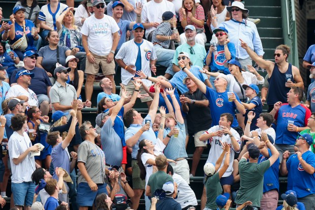 Fans reach for a home run ball hit by Dodgers third baseman Max Muncy in the eighth inning against the Cubs on Wednesday, Aug. 5, 2026, at Wrigley Field. (Eileen T. Meslar/Chicago Tribune)