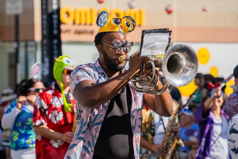 A marching band member in a WALL-E hat plays Earth, Wind & Fire's "September" as the band moves down 2nd St.