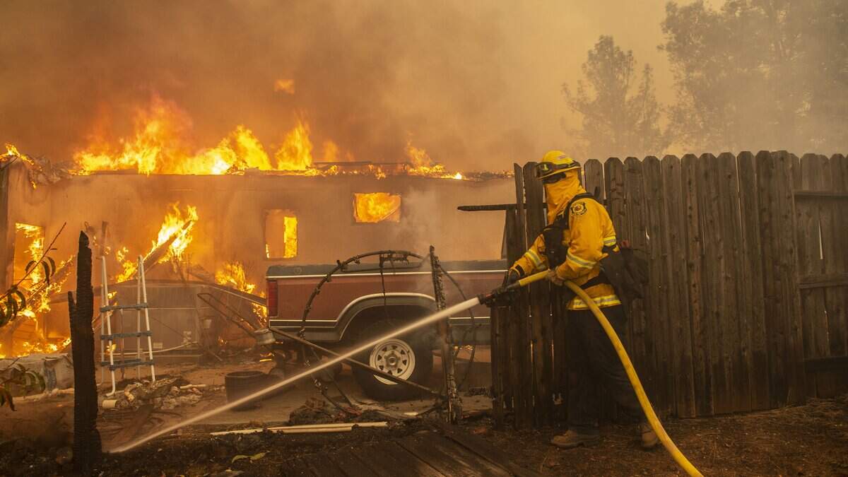 A firefighter works a line to prevent the Camp Fire from spreading near a home on Pentz Road in Paradise on Thursday, Nov. 8, 2018. Lawmakers are debating potential changes to how the state handles utility-caused wildfires.