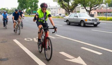 A man riding a bicycle giving a thumbs up