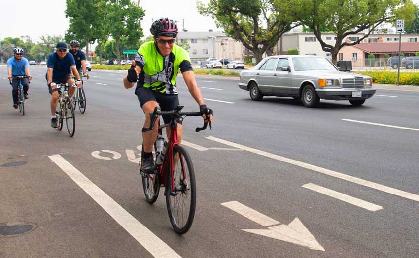 A man riding a bicycle giving a thumbs up