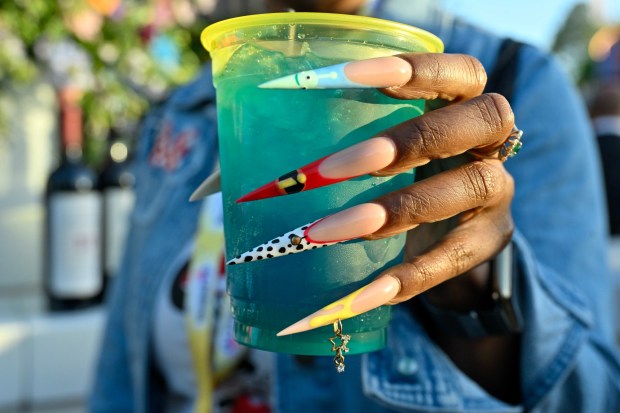 Sharronda Williams dons Disney-inspired nails as she holds the new Celebration Cocktail - tequila, rum, vodka and glittery blue raspberry lemonade, topped with sprite and garnished with a cherry - during a media preview of Disneyland 70th anniversary celebration in Anaheim, CA, on Wednesday, May 14, 2025. Disneyland is celebrating its 70th anniversary from May 16, 2025 through summer 2026.(Photo by Jeff Gritchen/MediaNews Group/Orange County Register via Getty Images)