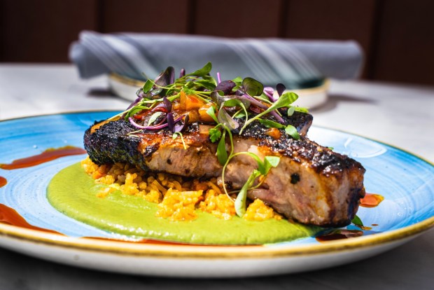 The new Heritage Pork Chop at Mia's is grilled in apple juice brine and paired with calabaza purée, Spanish rice pilaf and mango chutney. (Katie Itaya)