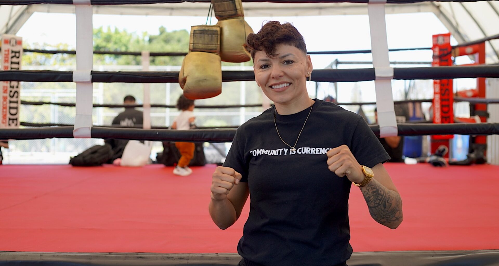 A woman posing for a photo in front of a boxing ring.