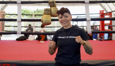 A woman posing for a photo in front of a boxing ring.