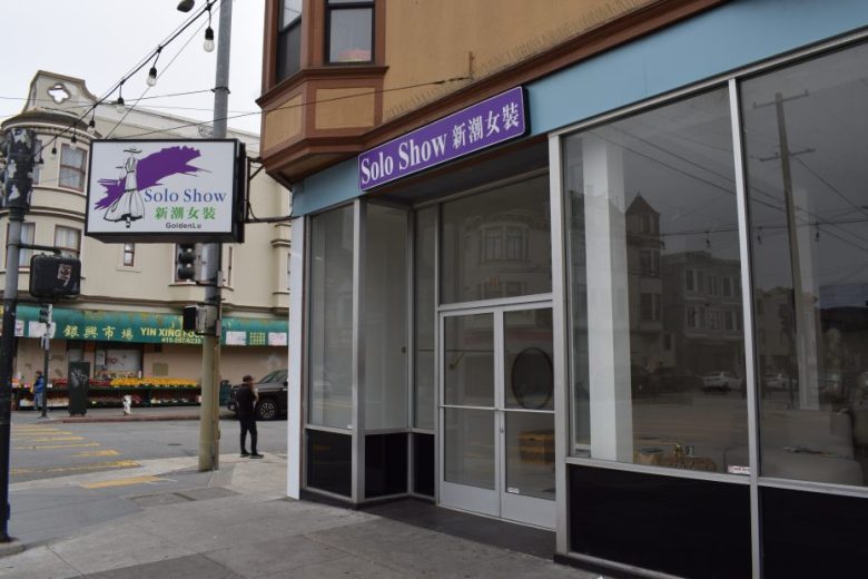 A storefront with large windows and a “Solo Show” sign in English and Chinese above the entrance on a city street corner.