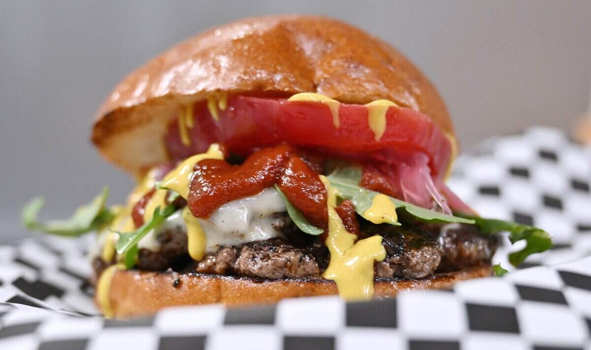 The Baddy Patty, two seasoned burger patties with Havarti cheese, baby arugula, Badd Blood ketchup, The Gold pickled mustard, pickled red onions and an heirloom tomato slice is offered by Tommy Marquez at Badd Burgers, located in Strummers in the Tower District. Photographed Thursday, July 30, 2026 in Fresno.