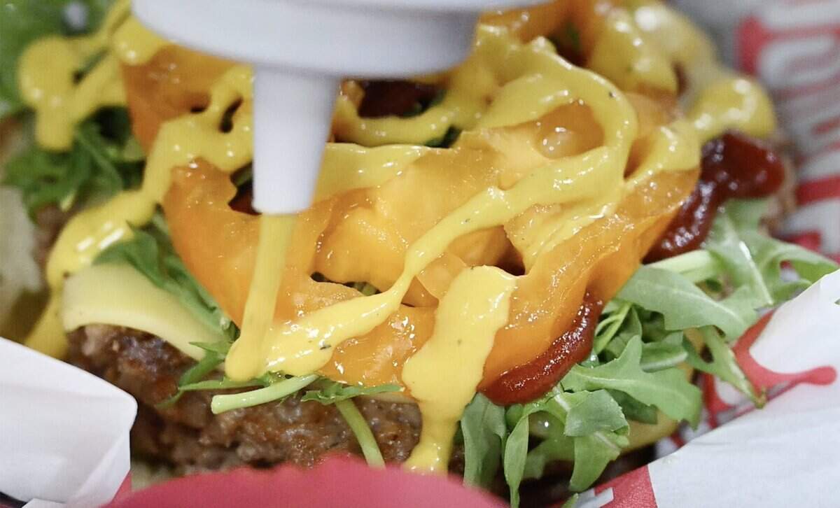 Pickled mustard is added over an heirloom tomato slice as Tommy Marquez creates a new burge rorder at Badd Burgers, located in Strummers in the Tower District . Photographed Thursday, July 30, 2026 in Fresno.