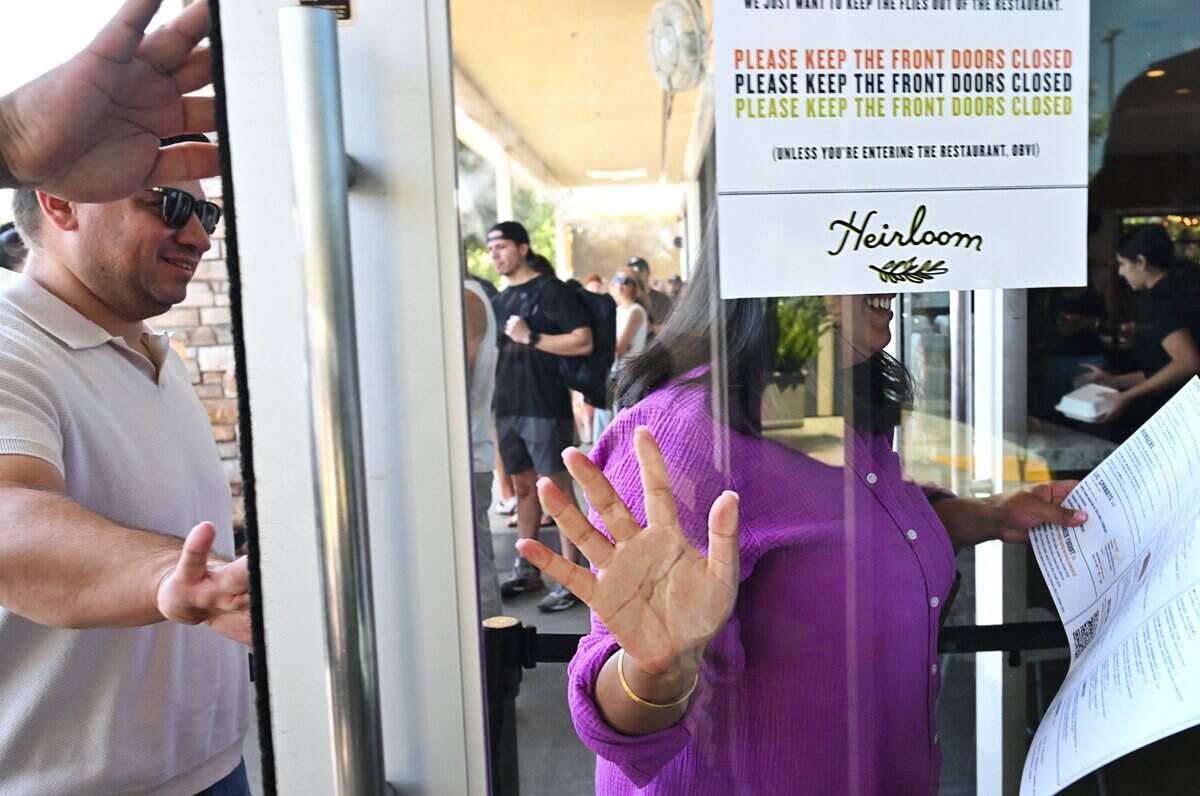 With hand placed against the front glass door, Nav Kaur enters Heirloom restaurant followed by two co-workers Friday afternoon, Aug. 21, 2026 in Fresno.