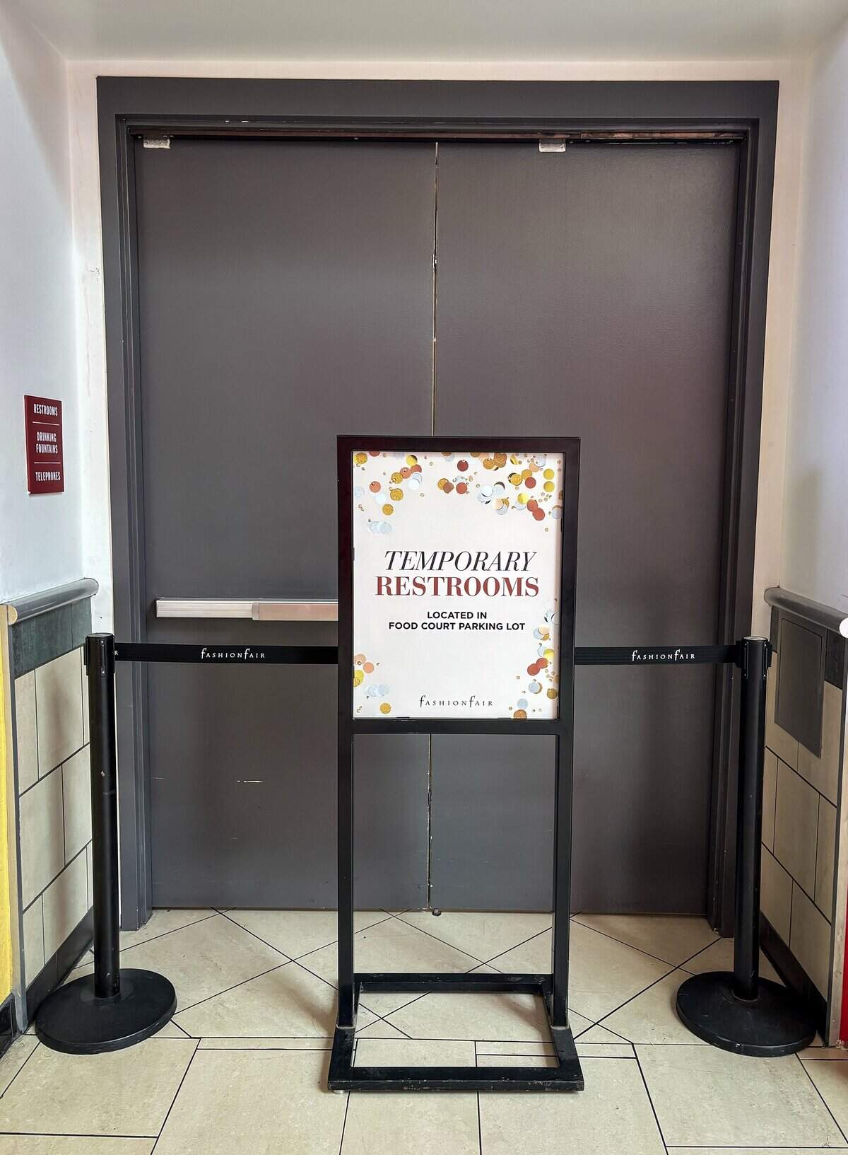 A sign posted at the closed restroom doorway points customers to temporary porta-potties in the parking lot outside the Fashion Fair mall food court on Monday, Aug. 10, 2026. The mall is having customers use porta-potties outside the food court as well as on the eastern entrance to the mall while working on restroom renovations.