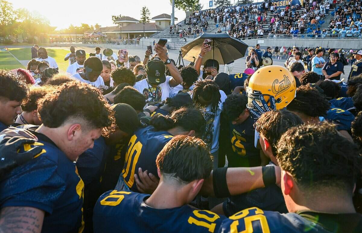 Members of the Sunnyside High School football team are joined by family and friends of Robert Peele III, a Sunnyside High School student who was struck and killed by a vehicle on his way to football practice last month, in a moment of prayer before the start of the Wildcats opener on Thursday, Aug. 20, 2026.