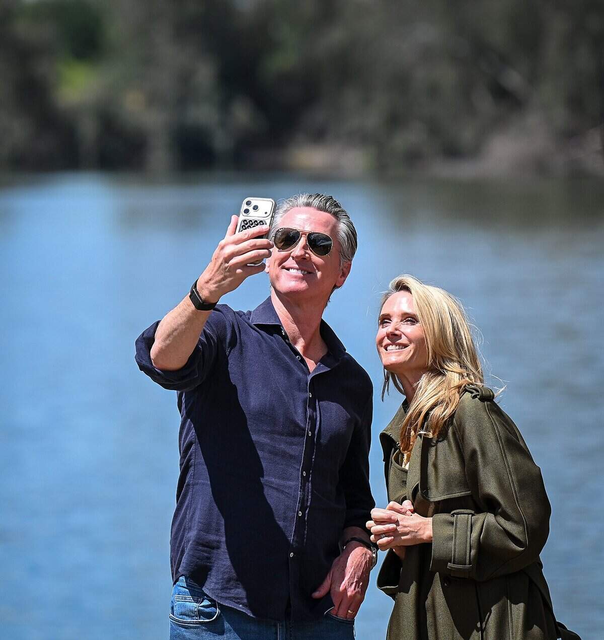 California Governor Gavin Newsom and his wife, first partner Jennifer Siebel Newsom, hold a FaceTime call after announcing the expansion of the state park system during a news conference near the Sycamore Island fishing dock along the San Joaquin River Parkway in Madera County on Wednesday, April 22, 2026.