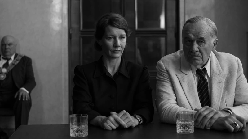 black and white image of woman and older man, sitting at table