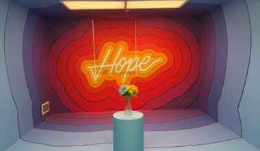 Neon "Hope" sign glowing inside a colorful immersive room with a pedestal holding fresh flowers at Hospital of Emotions.