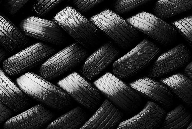 A tightly woven pattern created by overlapping black car tires, viewed from above in black and white.