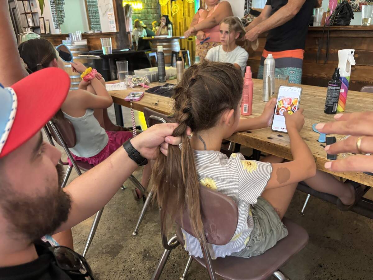 Sean Cox practices French braiding his daughter’s hair at the Pints and Ponies event, held by Strands Aveda Salon at Nitty’s Cider in East Sacramento on Monday.