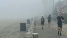 Joggers on the Mission Beach boardwalk, Saturday, appeared through the fog, August 29, 2026.