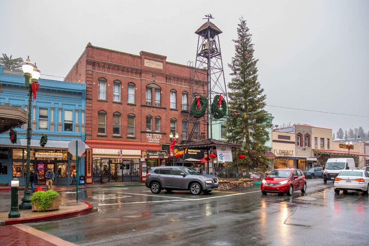 Main Street shows a small-town setting with a range of local shops. Many of the storefronts present Christmas-themed window displays during the holiday season. Placerville, CA. December 19, 2025.