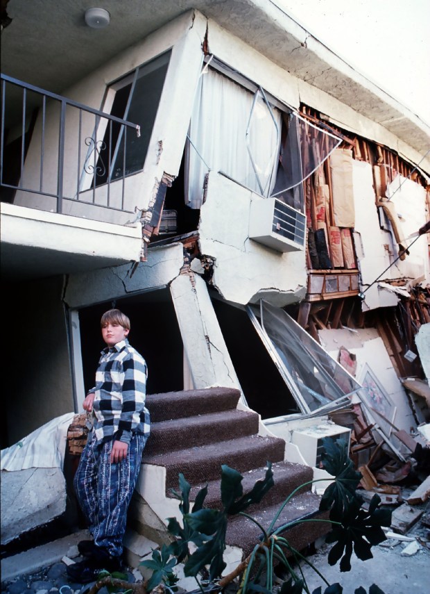 A young resident sits on the detached staircase leading to his family's upstairs apartment that was destroyed by the Northridge earthquake on the morning of Jan. 17, 1994. ..(Photo by Leonard Ortiz, Orange County Register/SCNG)