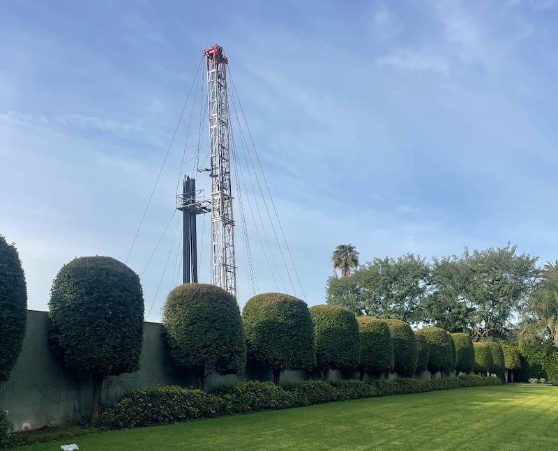 The Murphy site can be seen behind trees and landscaping. The tall drill site towers over the trees in front.