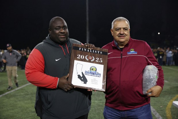 St. Pius' Head Coach, Devah Thomas, left, poses for a photo with the runner-up trophy after his team lost to Ventura, 63-28, in the CIF-SS Division 6 football championship game at St.Pius X-St. Matthias Academy in Downey on Saturday, Nov. 29, 2025. (Photo by Trevor Stamp, Contributing Photographer)