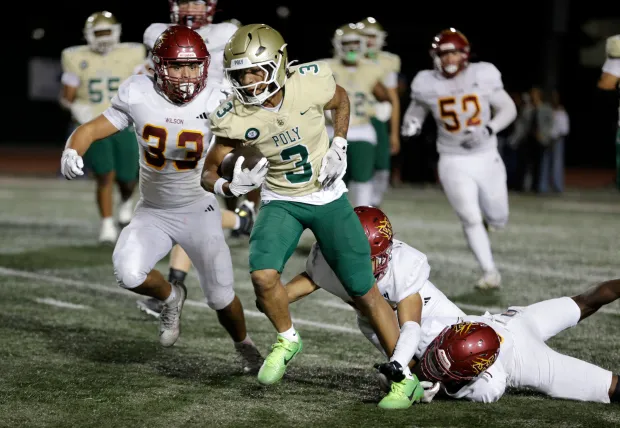 Long Beach Poly's Jayden Coley (3) tries to get away from Wilson's Dylan Sula (33), Luis Castro (44), and Cahmarr Davis (8) in Long Beach, CA, on Friday, Oct. 17, 2025. (Photo by Tracey Roman, Contributing Photographer)