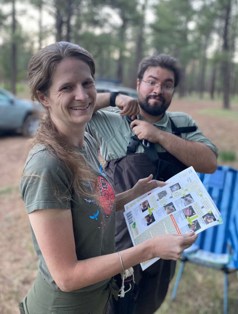 a woman and man among trees, looking at the camera