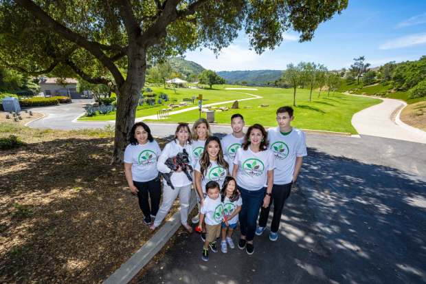 Members of Toxic-Free OC, a grassroots environmental organization, who live adjacent to Canyon View Park in Aliso Viejo, pose for a photo at the entrance to the park on Wednesday, April 17, 2024. They are from left: Zulma Alvarez, Melissa Christian, with her dog, Dakota, Tracy Blum, Carolyn McCuan, her husband, Charles, and children Caden 3, and Caylee, 5, Christine Hurden, and Brendan Brudevold. Members of the group have reported a series of debilitating illnesses as well as their pets due to their proximity to the park over the past few years. (Photo by Mark Rightmire, Orange County Register/SCNG)