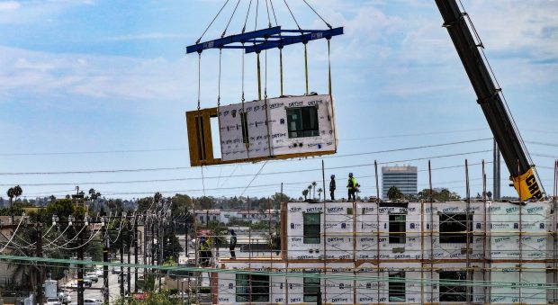 Workers lift the last prefab section of a 65-unit apartment complex in Midway City, CA, on Thursday, August 27, 2026. American Family Housing is building Casa Colibri from prefabricated sections built in Utah. They started placing the sections eight days ago. (Photo by Jeff Gritchen, Orange County Register/SCNG)