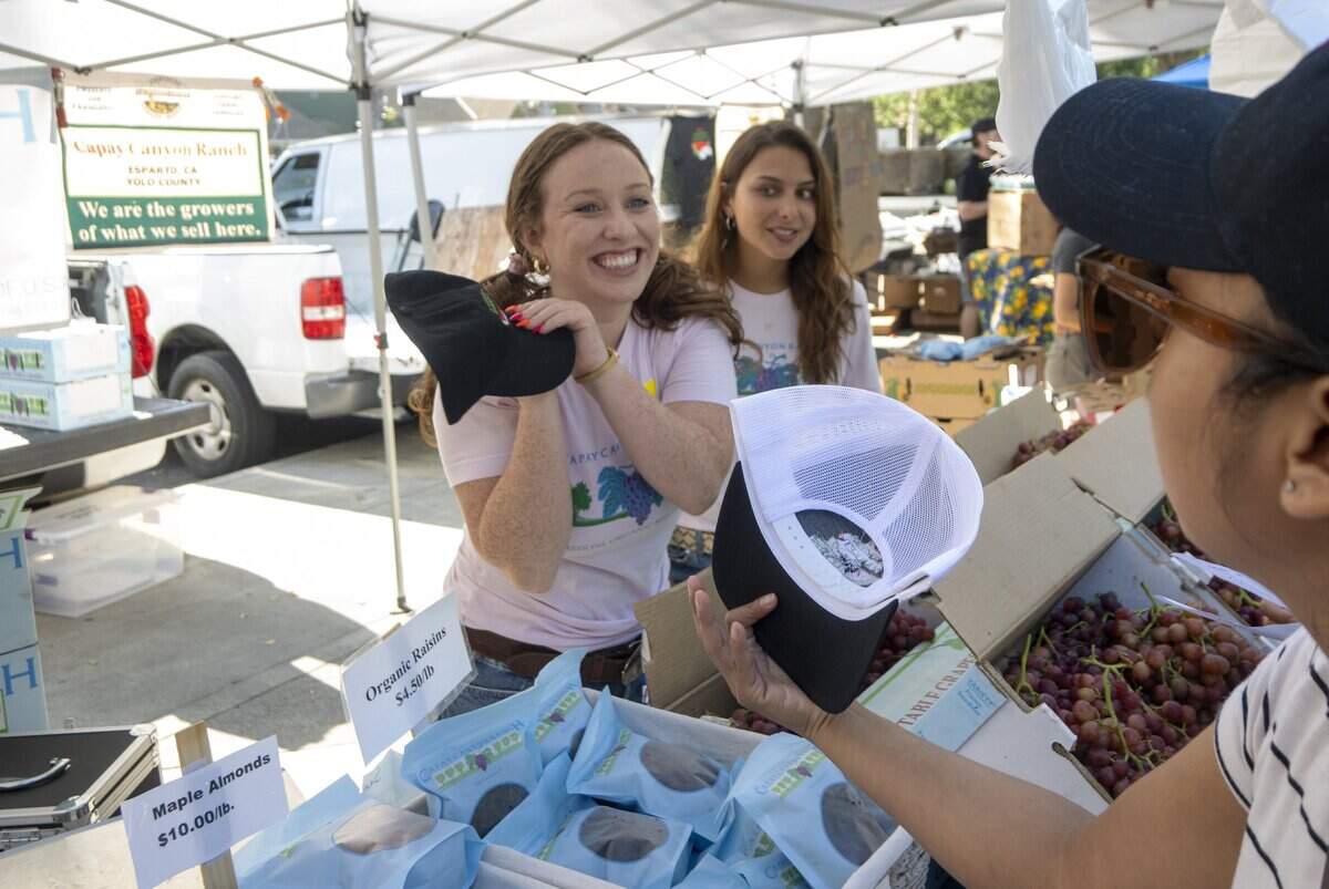 Alex Barth of Capay Canyon Ranch in Esparto reacts after Amelia Chase presents her a Davis Farmers Market 50th anniversary cap on Saturday, Aug. 1, during a celebration of the market's history in Davis.