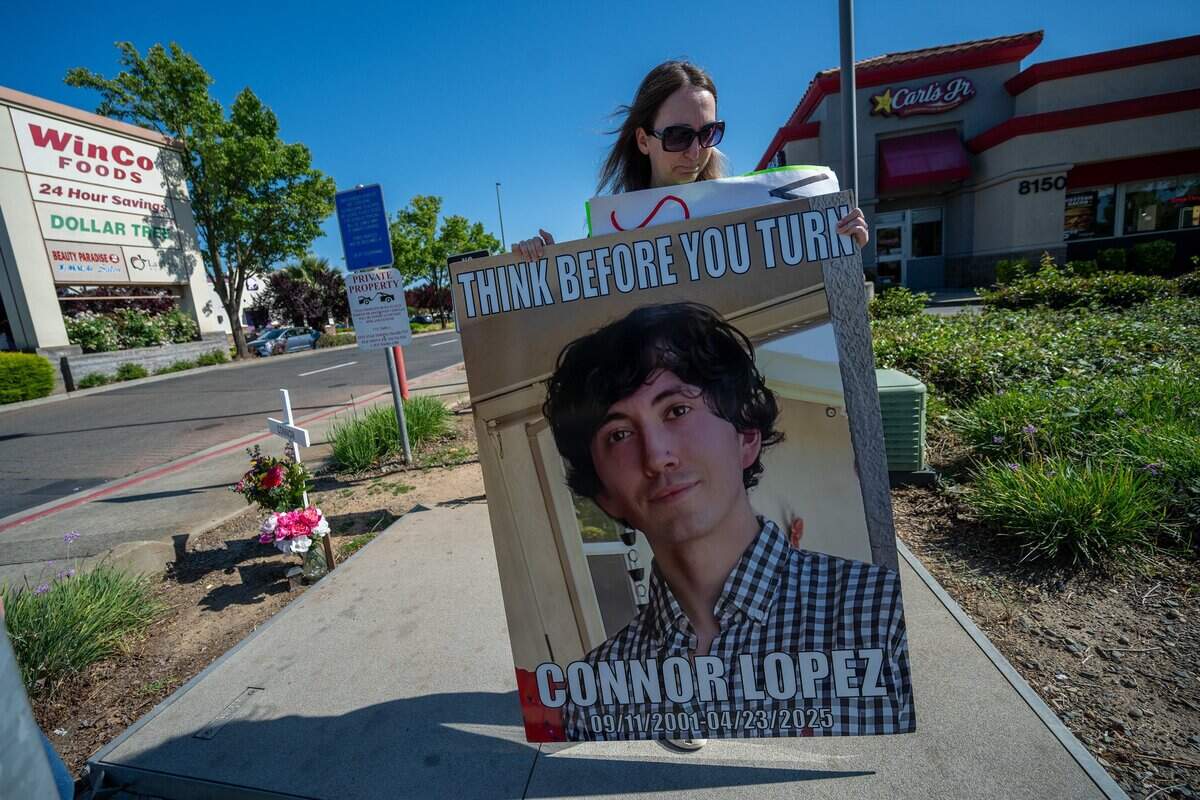 Allison Lyman carries a sign back to her car on April 29, after spending an hour near the intersection where her son, Connor Lopez, was killed when a motorist turning across traffic struck him while he was riding his motorcycle in April 2025. The sign aims to raise awareness among motorists to think before they turn. Lyman returns to the intersection along Sheldon Road every Wednesday during the same hour her son was killed.