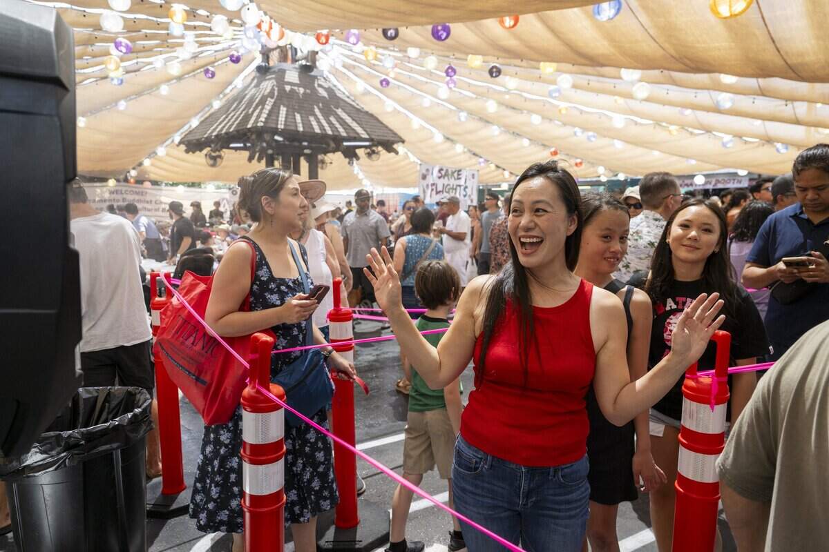 Assemblymember Stephanie Nguyen cools down under a water mister as she waits in line to order food at the 80th annual Japanese Food & Cultural Bazaar at the Buddhist Church of Sacramento on Saturday.