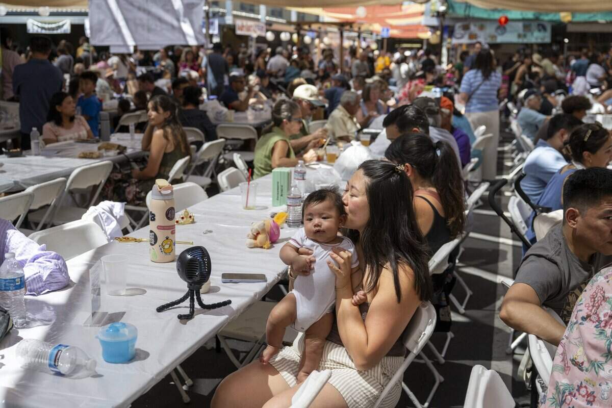 Fion Chu embraces her son, Guy, as they cool in front of a table fan at the 80th annual Japanese Food & Cultural Bazaar at the Buddhist Church of Sacramento on Saturday.