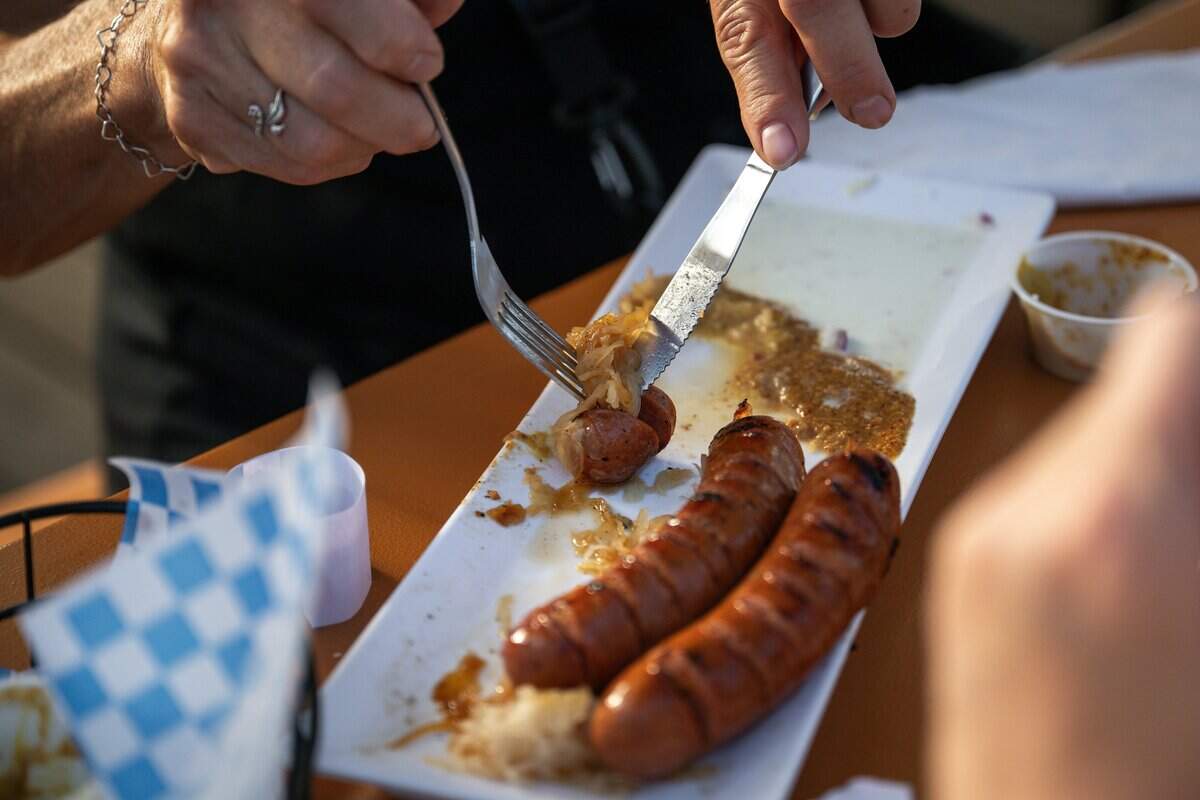 A customer eats a German sausage at the opening of Der Biergarten Waterfront in Old Sacramento on Friday.