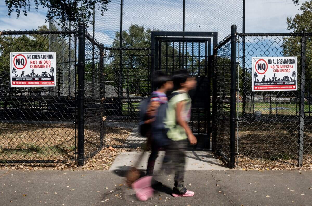 D.W. Babcock Elementary School students walk on Friday past signs opposing the construction of a nearby crematorium in Sacramento.