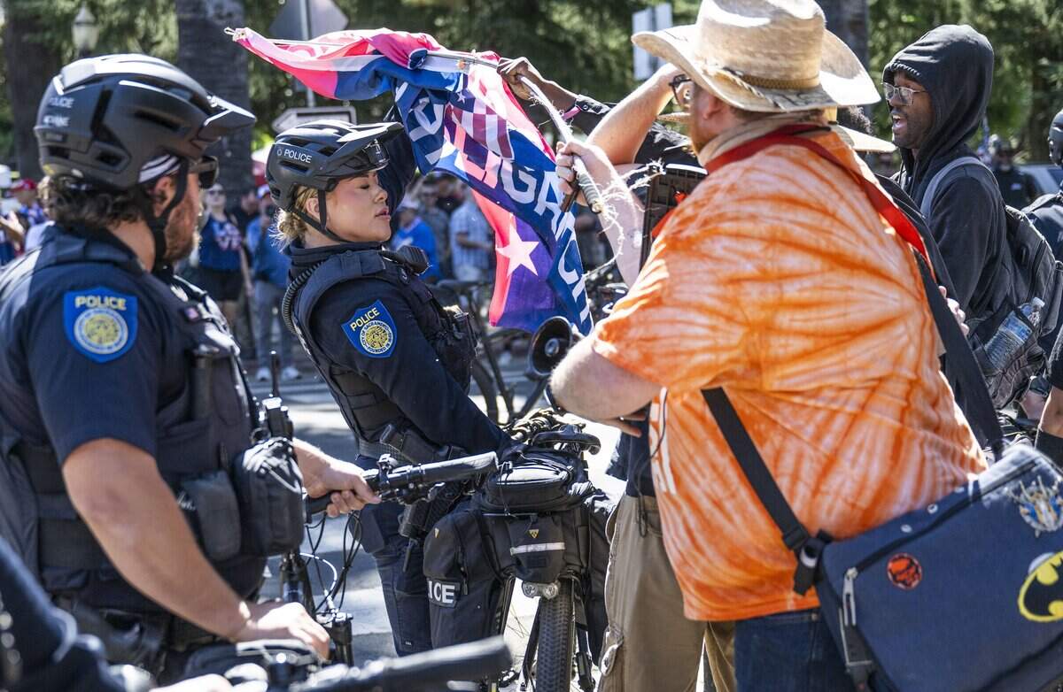 A Sacramento police bike officer struggles with a flag on 10th Street as protesters demonstrate against online political influencer Nick Shirley's appearance at a Republican news conference at the state Capitol on Wednesday, Aug. 26, 2026.