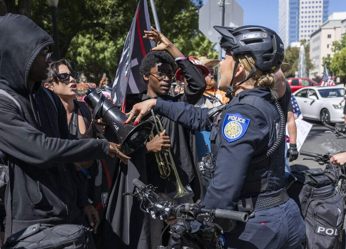A Sacramento police officer pushes down a megaphone held by a protester demonstrating against online political influencer Nick Shirley's appearance at a Republican news conference at the state Capitol on Wednesday, Aug. 26, 2026.