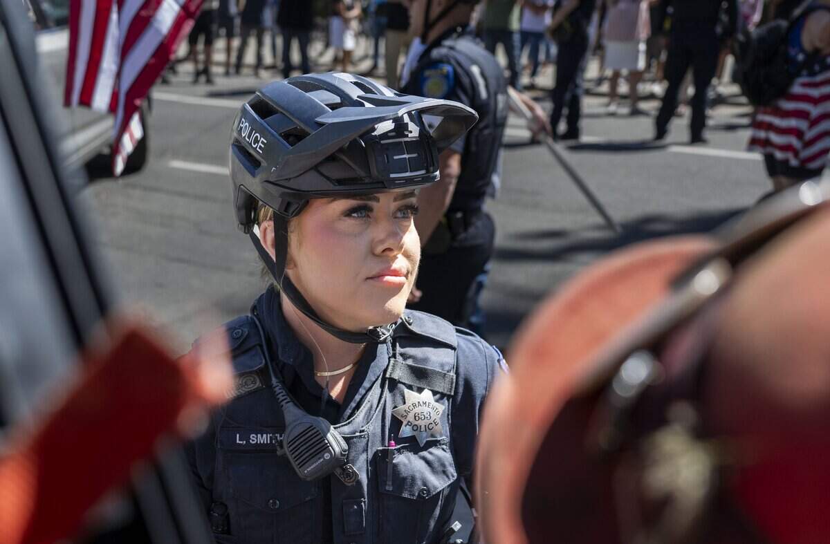 A Sacramento police officer stands in front of a group of protesters demonstrating against online political influencer Nick Shirley's appearance at a Republican news conference at the state Capitol on Wednesday, Aug. 26, 2026.