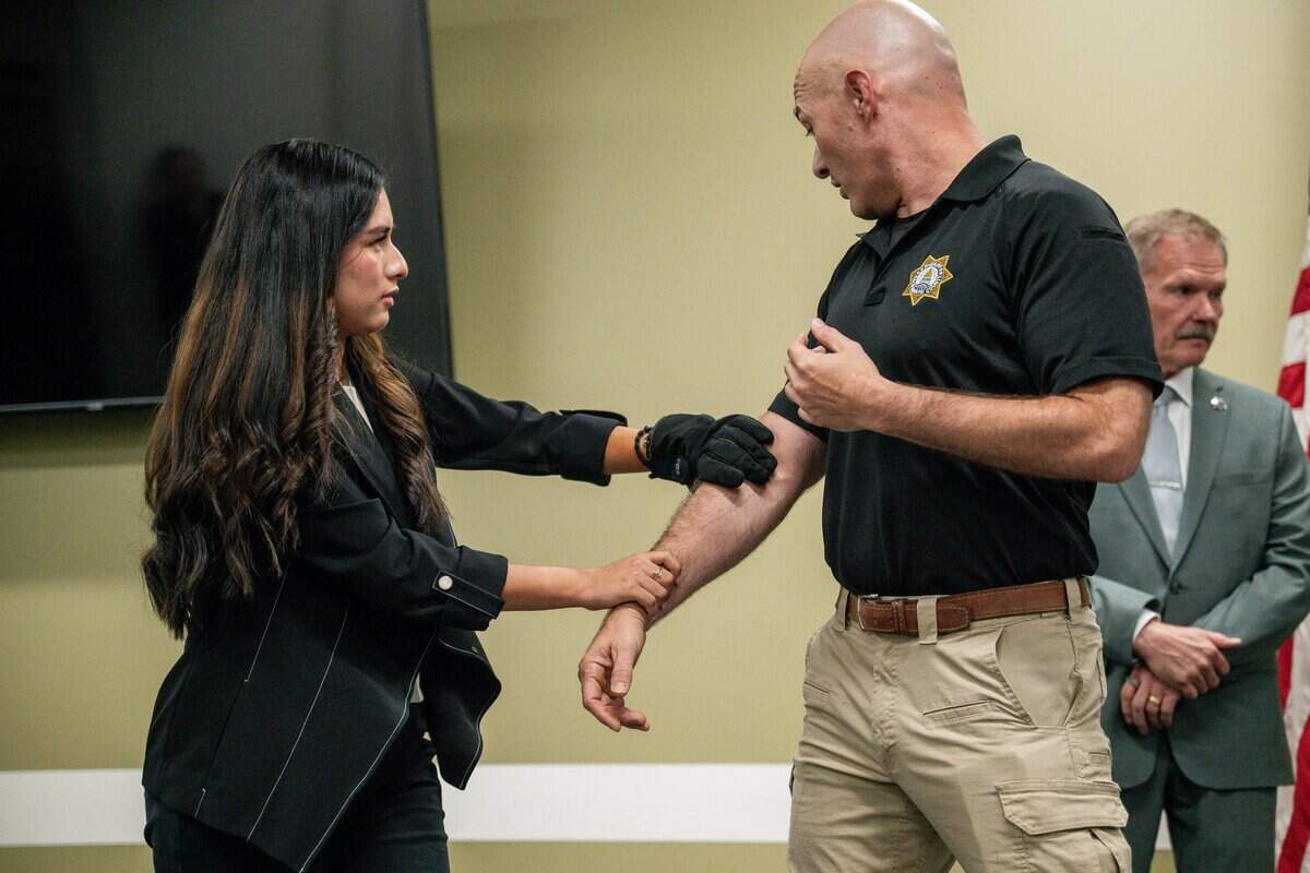 Lt. Will Vernon, right, participates in an electric glove demo session during a news conference at the Sacramento County Sheriff's Office Headquarters on Thursday.