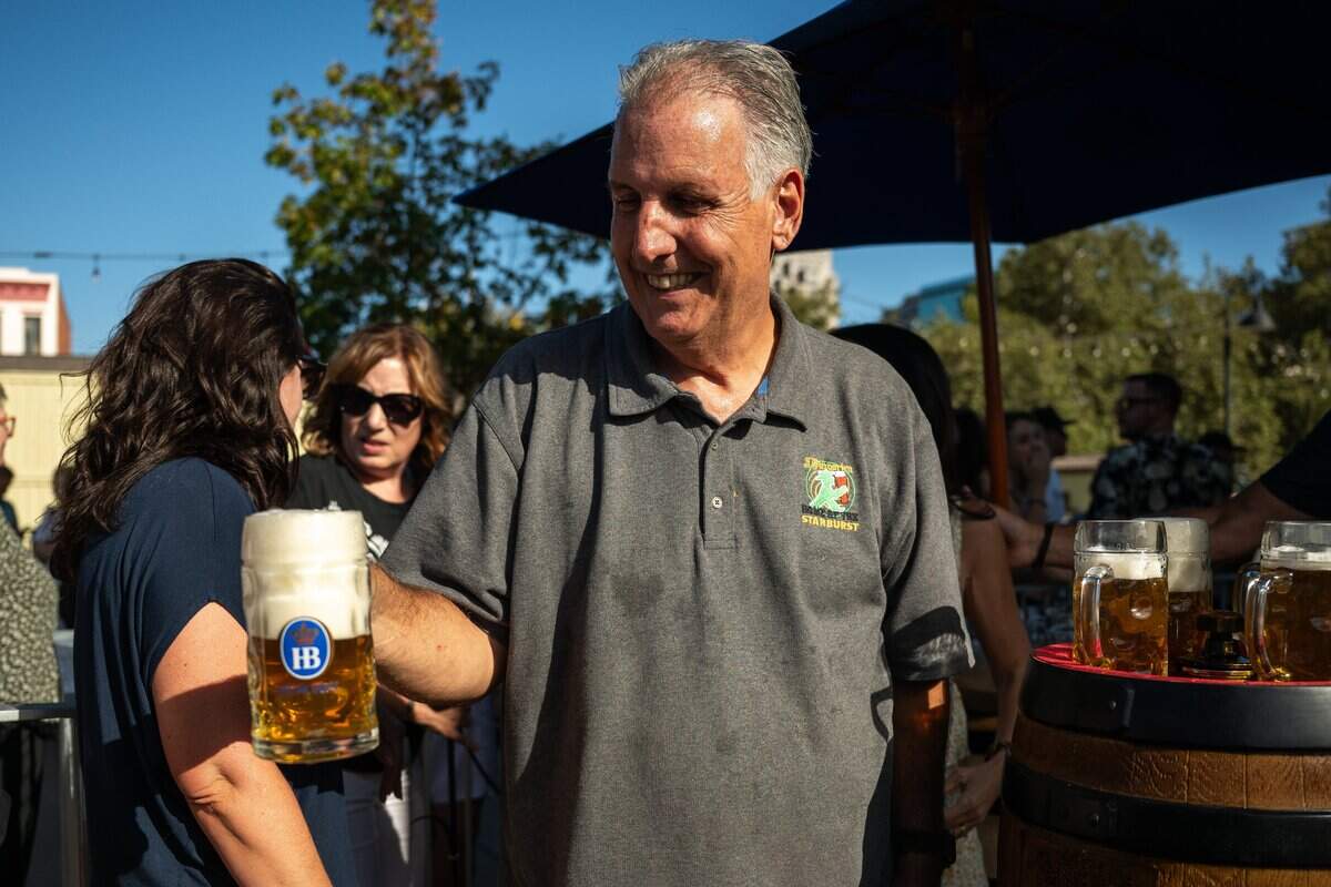 Owner Sean Derfield passes a mug of beer at the opening of Der Biergarten Waterfront in Old Sacramento on Friday.