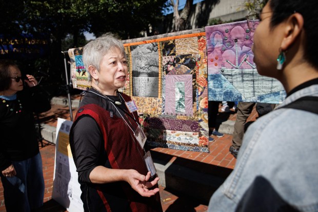 Former Save Our National Archives communication co-chair Jeanie Chooey Low shows quilts that she's made with her parents' printed government documents during a press conference where U.S. Rep. Kevin Mullin (CA-15) on Monday, Aug. 24, 2026, announced efforts to stop the planned closure of the National Archives at San Francisco facility located in San Bruno, Calif. (Dai Sugano/Bay Area News Group)