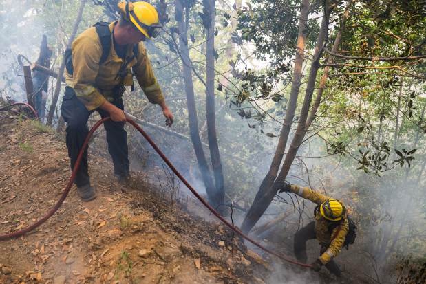 Firefighters work to put out a spot fire from the Timber Fire above Deetjen's Inn in Big Sur, Calif., Tuesday, Aug. 11, 2026. (AP Photo/Nic Coury)