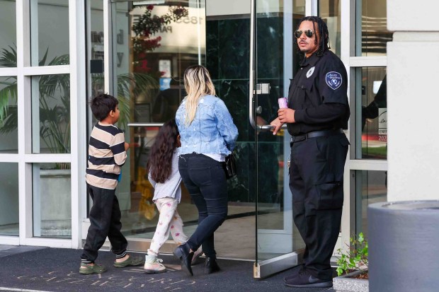 A woman with kids arrive for an immigration hearing as a security guard opens the door to the immigration court building in Concord, Calif., on Wednesday, Aug. 12, 2026. The Concord immigration court is holding mass hearings for immigrants facing deportation or seeking asylum. (Ray Chavez/Bay Area News Group)