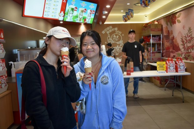 Zi Han and Zi Jia pick up free soft-serve ice cream cones at Mixue at the shop's grand opening on July 10. (Kate Bradshaw/Bay Area News Group)