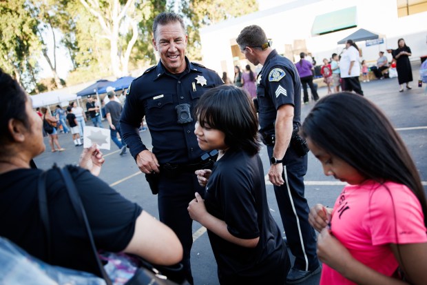 San Jose Police Department Lt. Todd Jennings mingles with Timothy Vasquez, 11, center, and his sister, Tania Vasquez, 10, as they receive police stickers during a National Night Out event in San Jose, Calif., on Aug. 4, 2026. The community event hosted by nonprofits ConXión to Community and Martha's Kitchen featured a free backpack giveaway, a petting zoo, face painting, free food, live music and others. (Dai Sugano/Bay Area News Group)