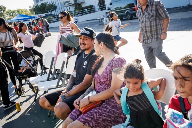 Gabriel Jimenez of San Jose, center, and his fiancée, Quetzalli Jimenez, enjoy watching live music by high school students during a National Night Out event in San Jose, Calif., on Aug. 4, 2026. The community event hosted by nonprofits ConXión to Community and Martha's Kitchen featured a free backpack giveaway, a petting zoo, face painting, free food, live music and others. (Dai Sugano/Bay Area News Group)